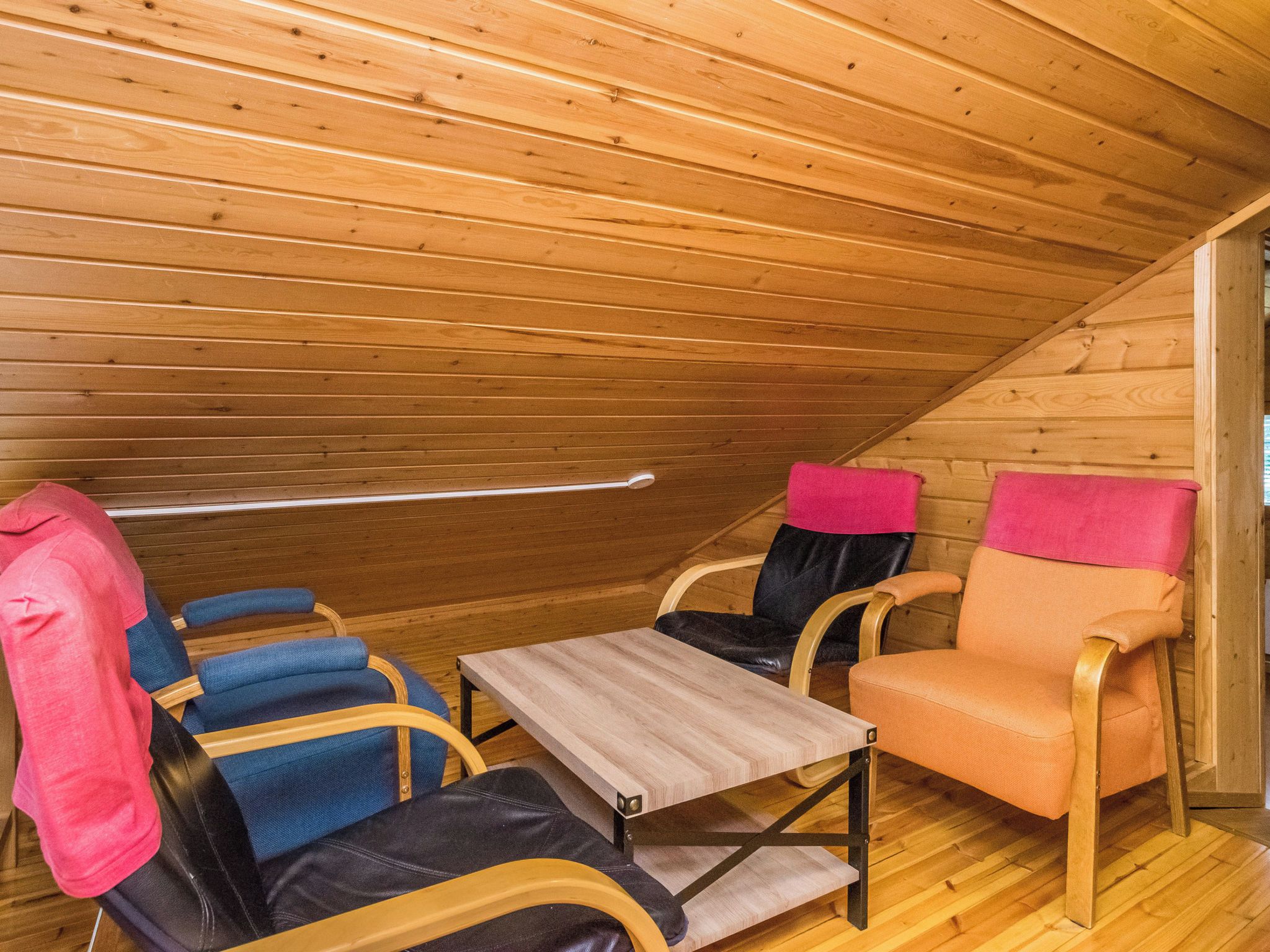 Un intérieur en bois avec un plafond en pente, une petite table et deux chaises.