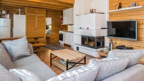 L’intérieur chaleureux d’un chalet, avec un décor en bois, une cheminée, un téléviseur et un canapé.