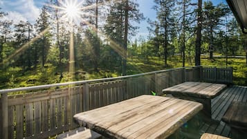 Een houten terras met banken met uitzicht op een bebost gebied.