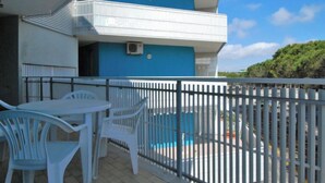 Un balcon avec une piscine, des chaises blanches et un immeuble bleu.