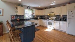 A modern kitchen with white cabinets, a black countertop, and a central island. - Creekside Mountain by AvantStay | Private Sauna (Asheville)