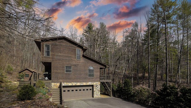 A two-story wooden cabin with a stone foundation, a garage, and a deck. - Creekside Mountain by AvantStay | Private Sauna (Asheville)