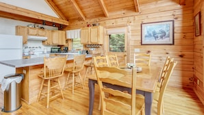 A wooden cabin with a kitchen, dining area, and a framed picture on the wall. - Incredible View, Hot Tub, Fire Pit, Grill & Foosball | Mountain Gem by AvantStay (Waynesville)