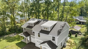 A two-story house with a garage, a covered porch, and a fenced yard. - Little Sycamore by AvantStay | Premier Location + Patio | Sycamore Cove Gem (Asheville)