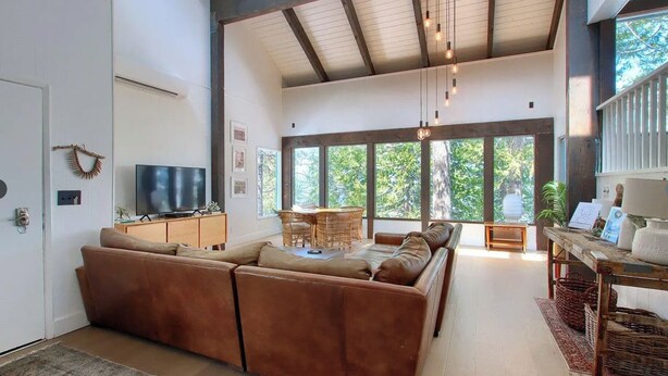 A spacious living room with a large sectional sofa, a dining area with a table and chairs, and a television on a cabinet.