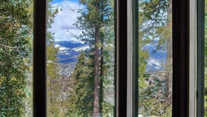 A window with a view of a forested mountain landscape.
