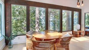 A room with a large window, wicker furniture, and a view of trees.