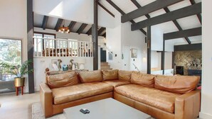 A spacious living room with a large L-shaped leather sofa, a white coffee table, and a stone fireplace.