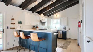 A modern kitchen with white cabinets, a blue island, and bar stools.