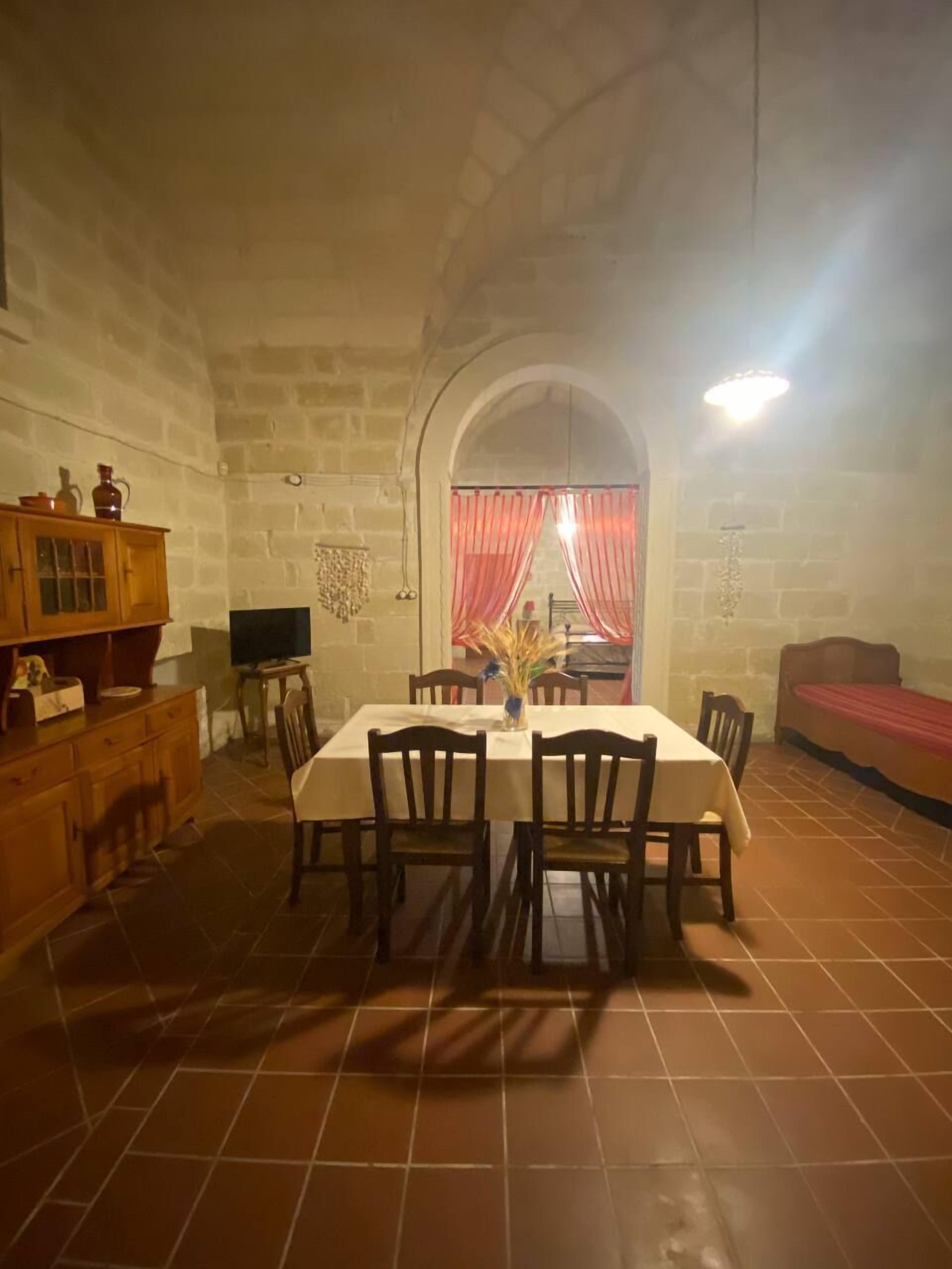 A dining area with a table set for four, surrounded by chairs, and a wooden cabinet to the left.