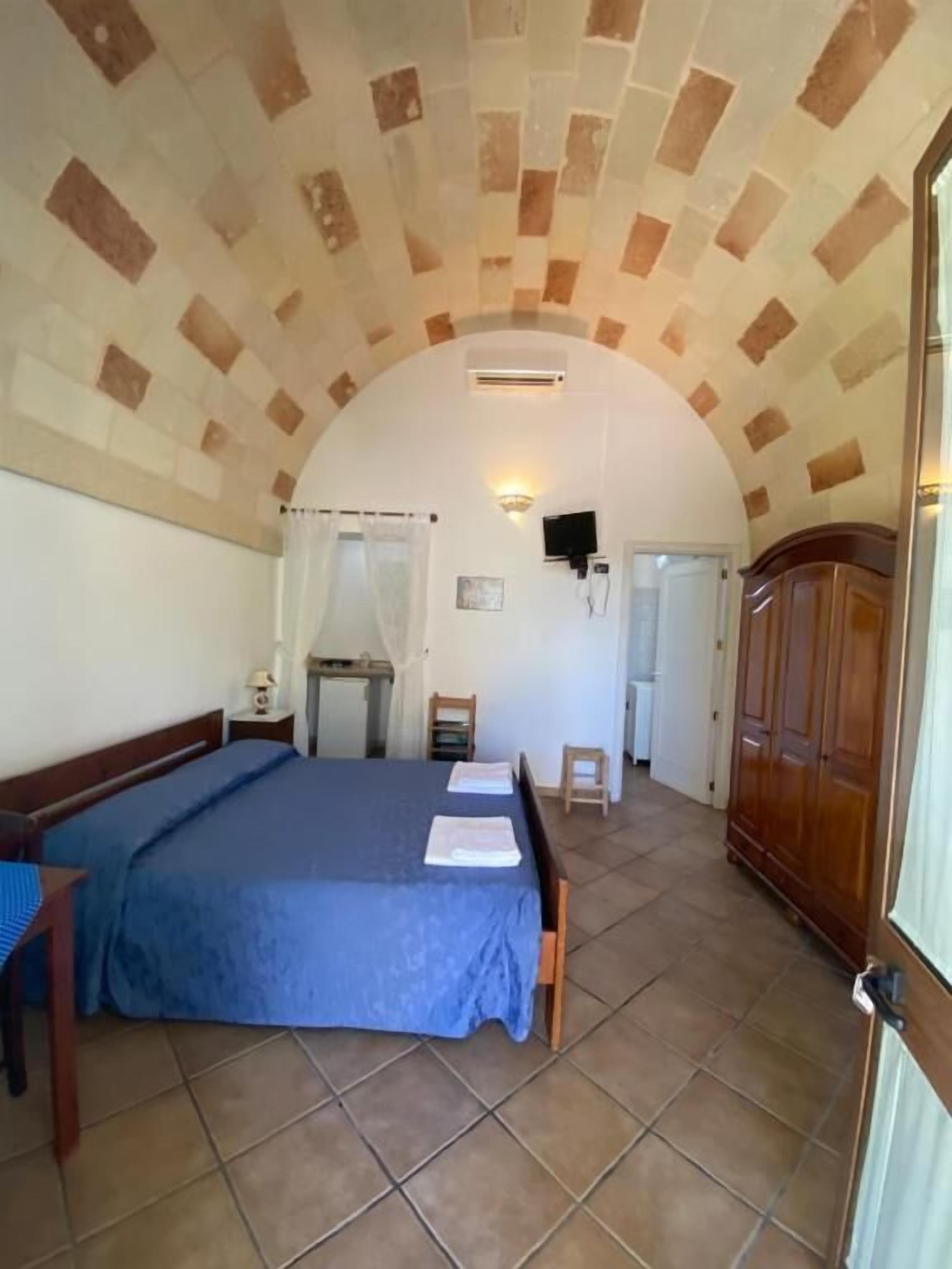Une chambre à coucher avec un grand lit, une armoire en bois, un bureau et une chaise.