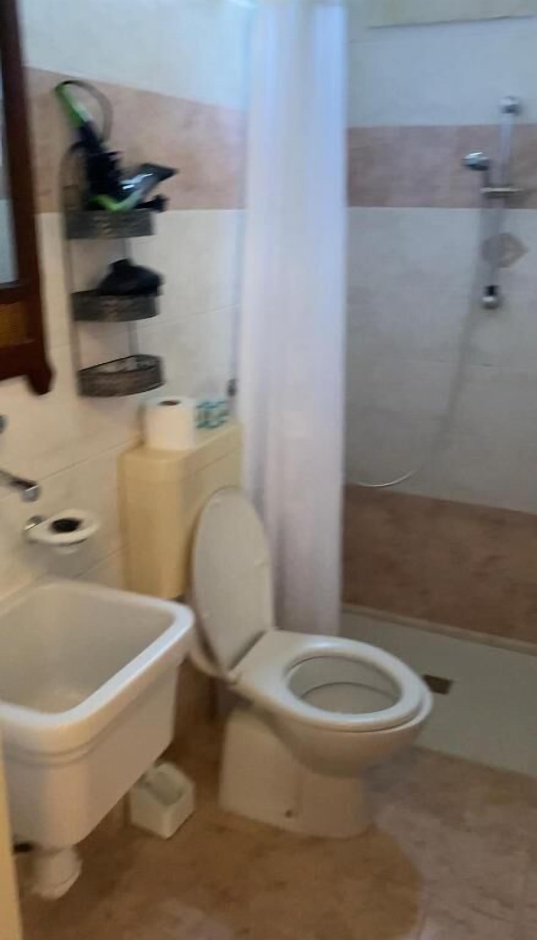 A bathroom with a toilet, sink, and shower.