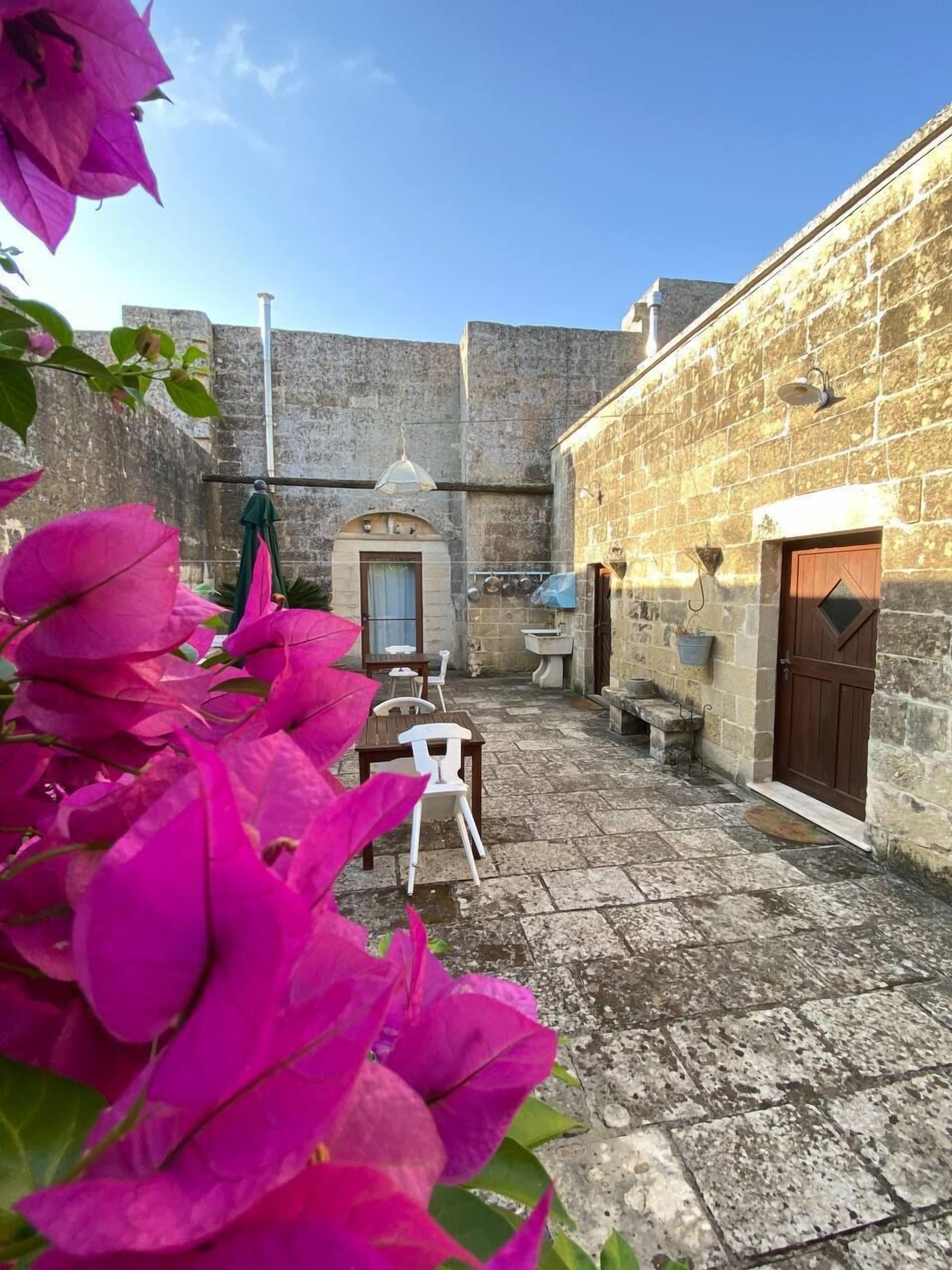 A courtyard with stone walls, a white chair, a table, and a door.