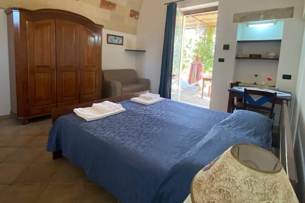 Un dormitorio con cama, armario, escritorio y silla.