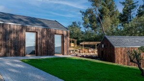A modern wooden building with a large sliding door and a covered outdoor seating area.