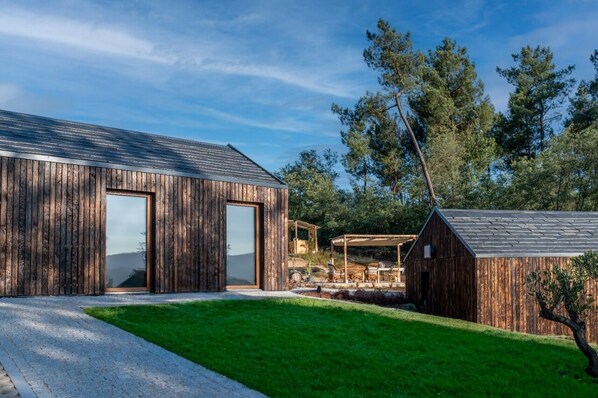 A modern wooden building with a large sliding door and a covered outdoor seating area.
