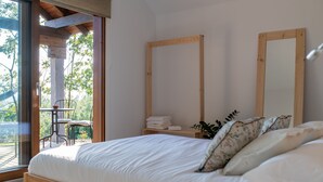 A bedroom with a bed, a wooden headboard, a large mirror, and a small table with chairs.