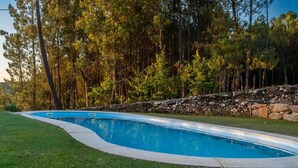 A swimming pool with a stone wall and trees in the background.