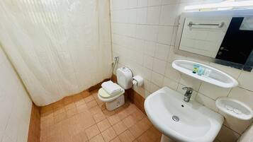 Un baño con inodoro, lavamanos y cortina de ducha.