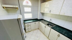 Uma cozinha compacta com armários brancos, pia e janela.