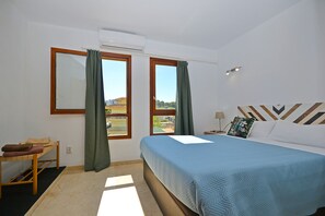 Une chambre à coucher avec un lit, une fenêtre, une table de chevet et une vue sur l’extérieur.