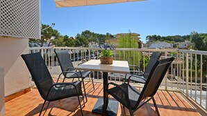 A balcony with a table and chairs, a potted plant, and a view of the surrounding area. - Oliva - Central apartment with air conditioning 150 meters from the beach in Mallorca (Alcúdia)