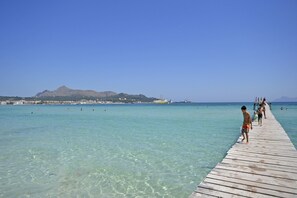 Une jetée en bois s’étendant dans une eau turquoise et limpide, avec une montagne en arrière-plan.