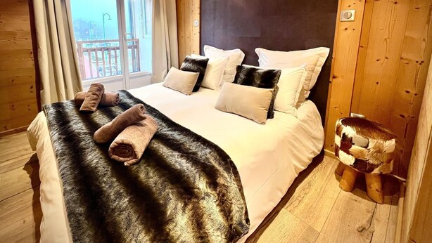 Un dormitorio con una cama grande, paredes de madera y dos luces fijadas a la pared.