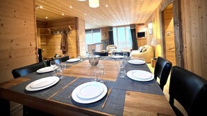 Un interior de madera con una mesa de comedor dispuesta para seis personas, un sofá y un televisor.