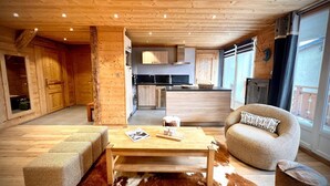 Interior acogedor de una cabaña con piso de madera, una mesa de centro, un sofá y una zona de cocina.
