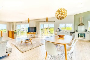 A spacious living area with a dining table, sofas, and a TV.