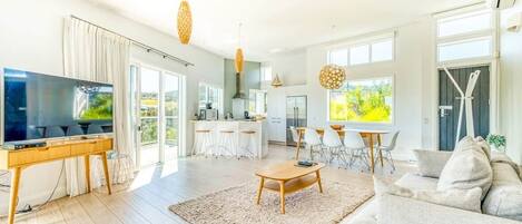 A spacious living area with a television, sofa, coffee table, and dining area.
