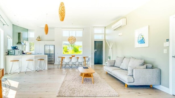 A spacious living area with a sofa, coffee table, and dining set.