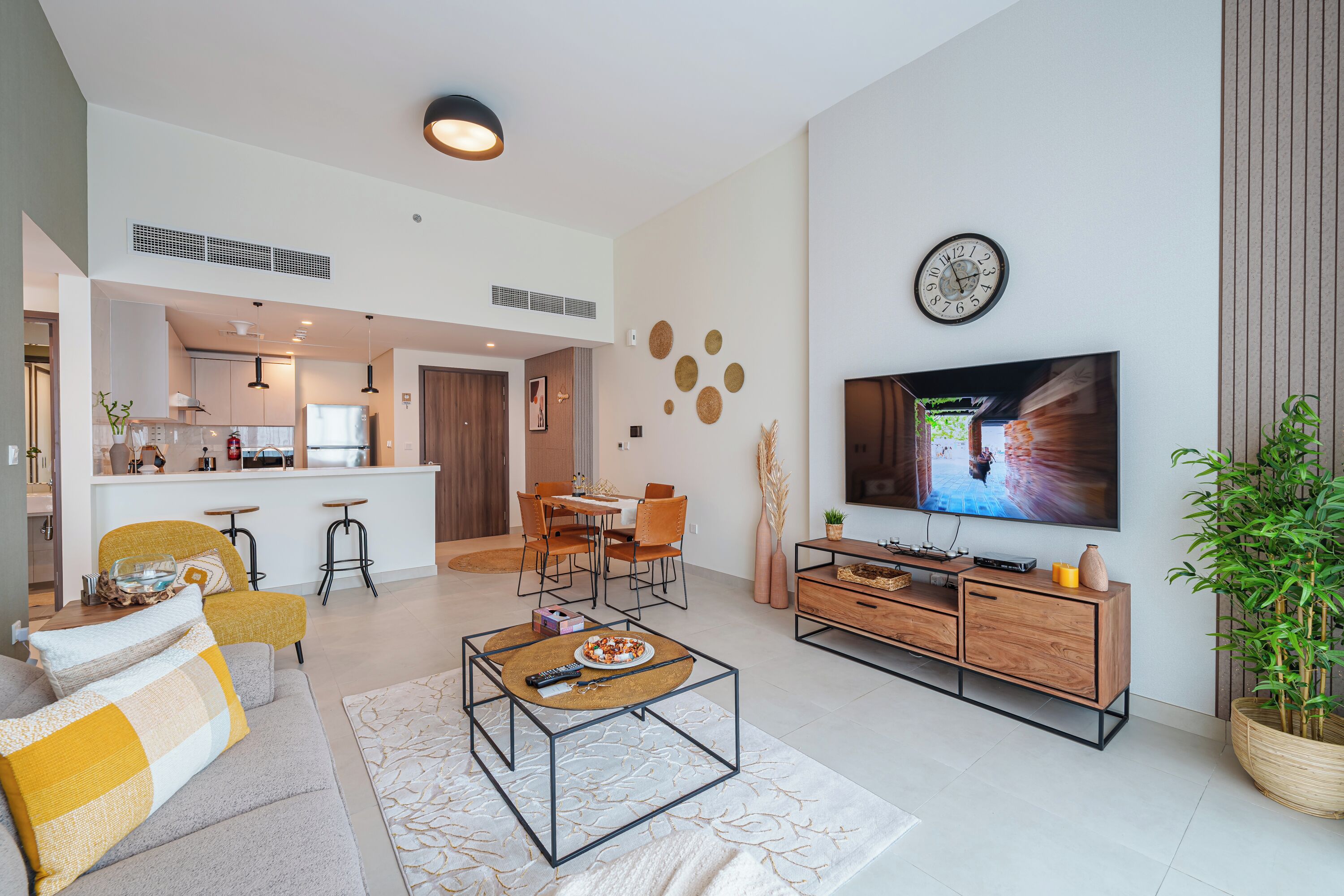 Un salon moderne comprenant un canapé, une table basse, un téléviseur et un coin repas avec des chaises et une table.