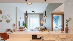 A modern kitchen with a stainless steel sink, overhead pendant lighting, and a dining area with a table and chairs.