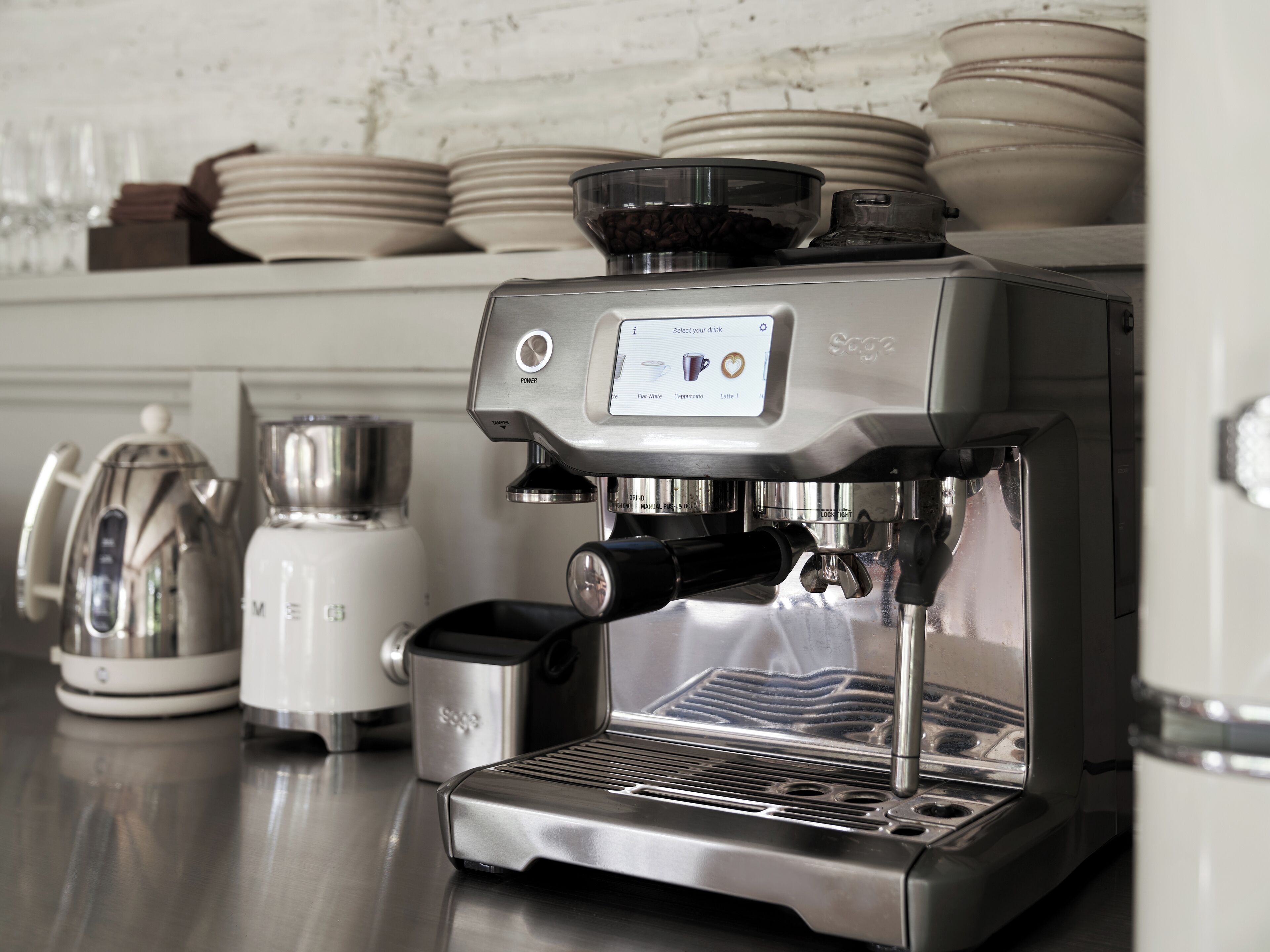 A commercial espresso machine with a digital interface, a milk frother, and a grinder.