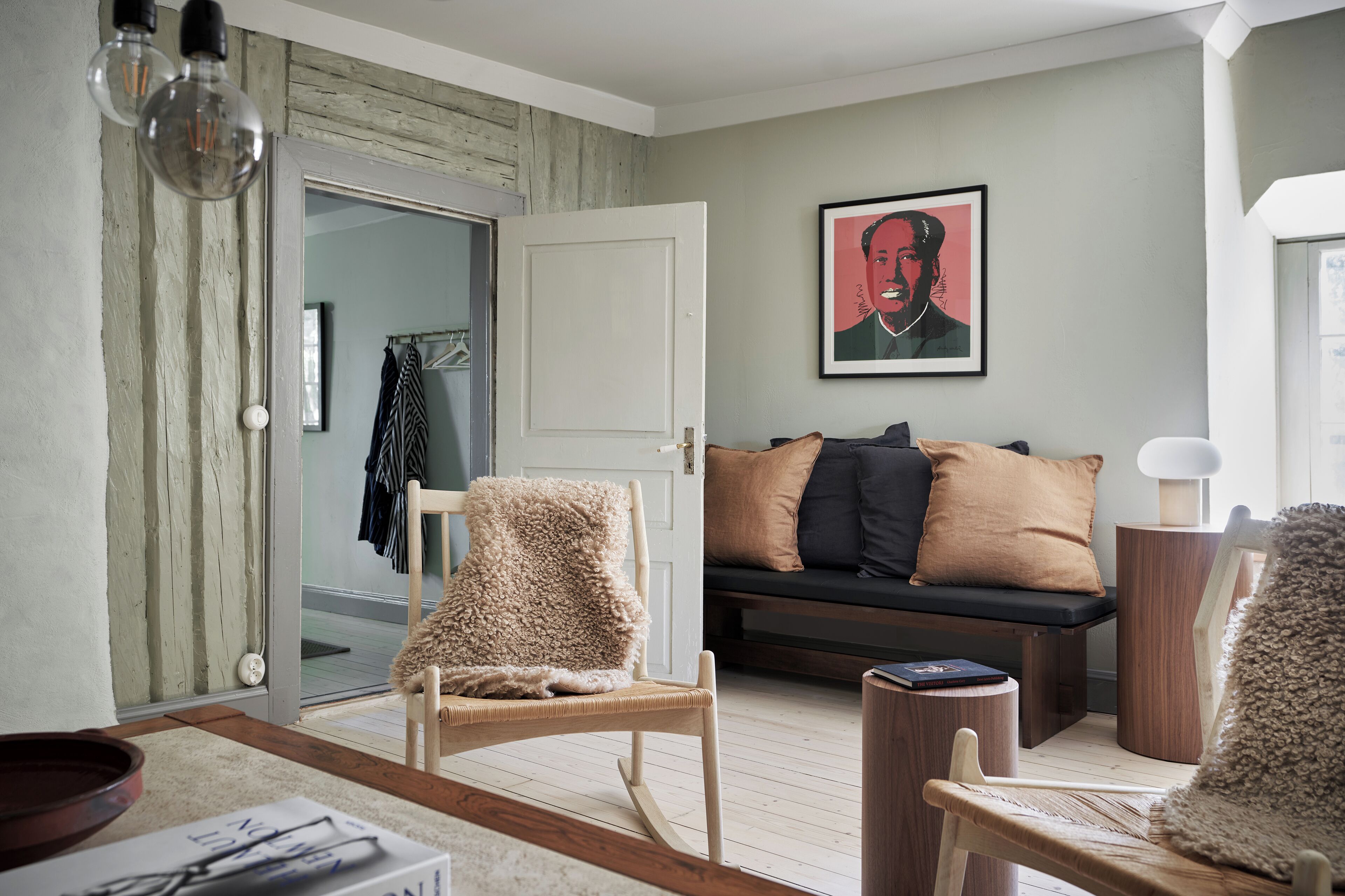 Ett vardagsrum med en soffa, en fåtölj, en lampa och en inramad tavla på väggen.