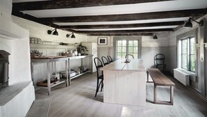 Uma cozinha espaçosa com uma ilha grande, vigas de madeira no teto e vista para o exterior através de amplas janelas.