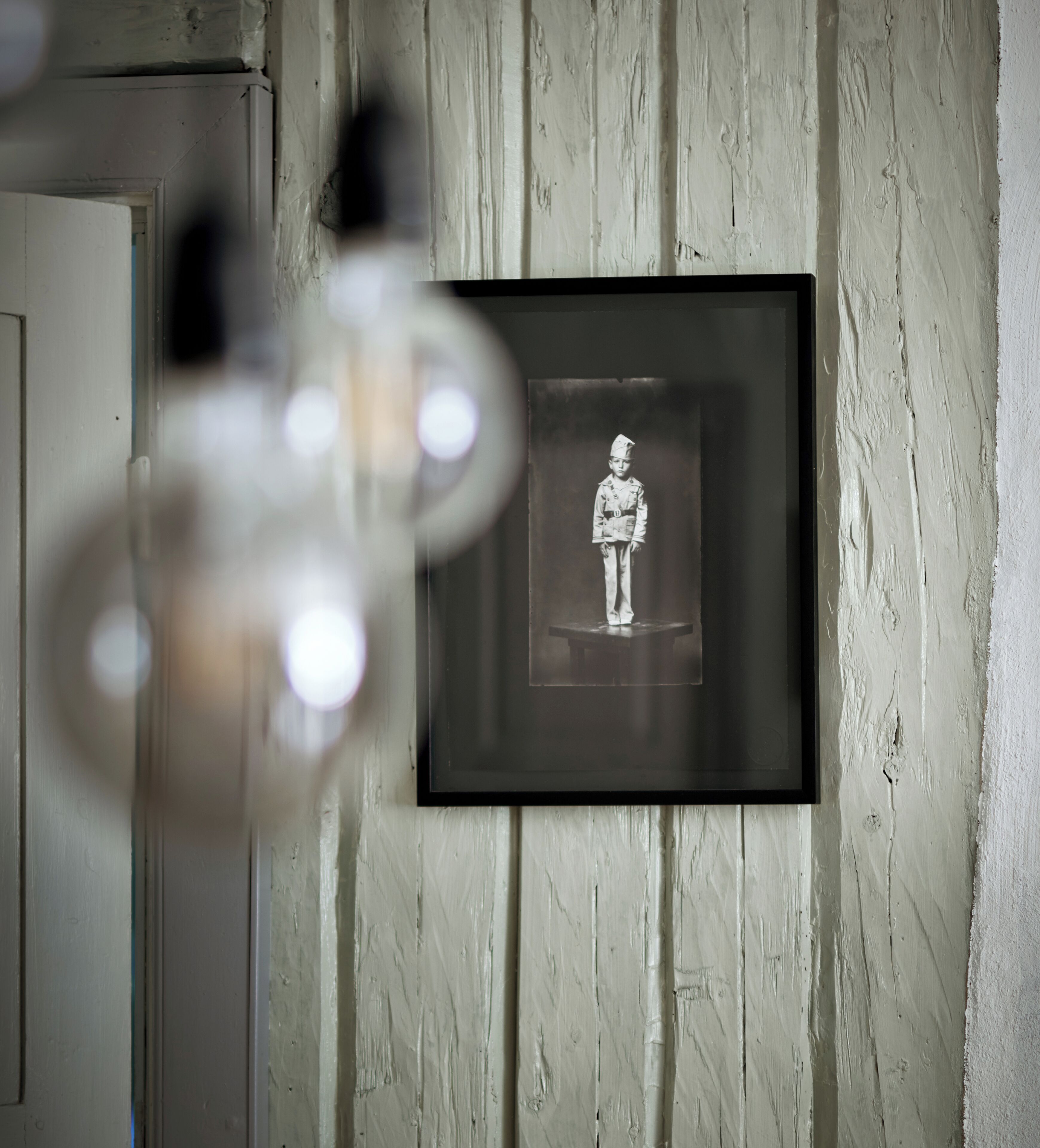 Une photographie en noir et blanc, encadrée, est accrochée à un mur dont la surface est texturée.