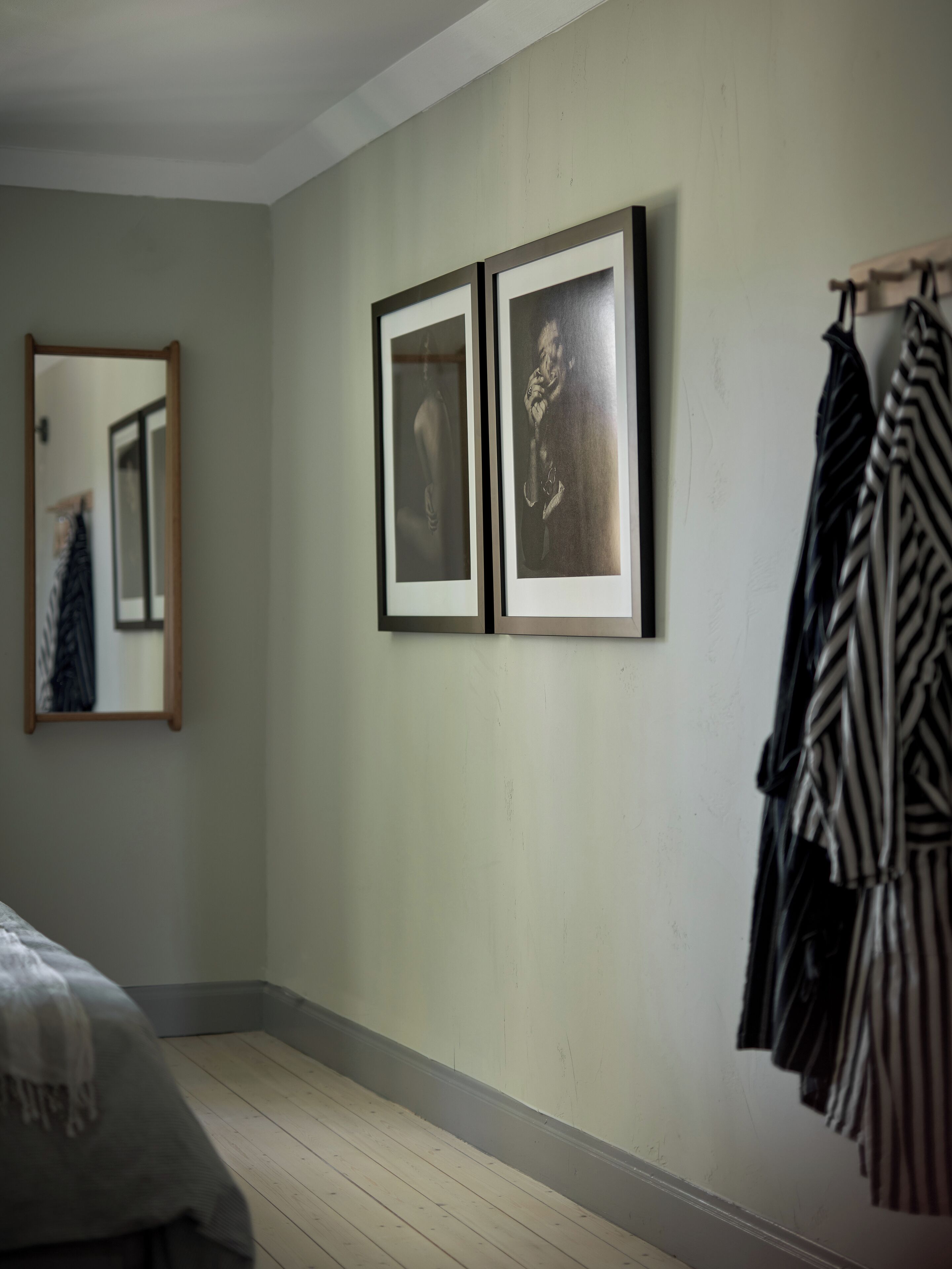 Una habitación con una cama, un espejo y dos cuadros en la pared.