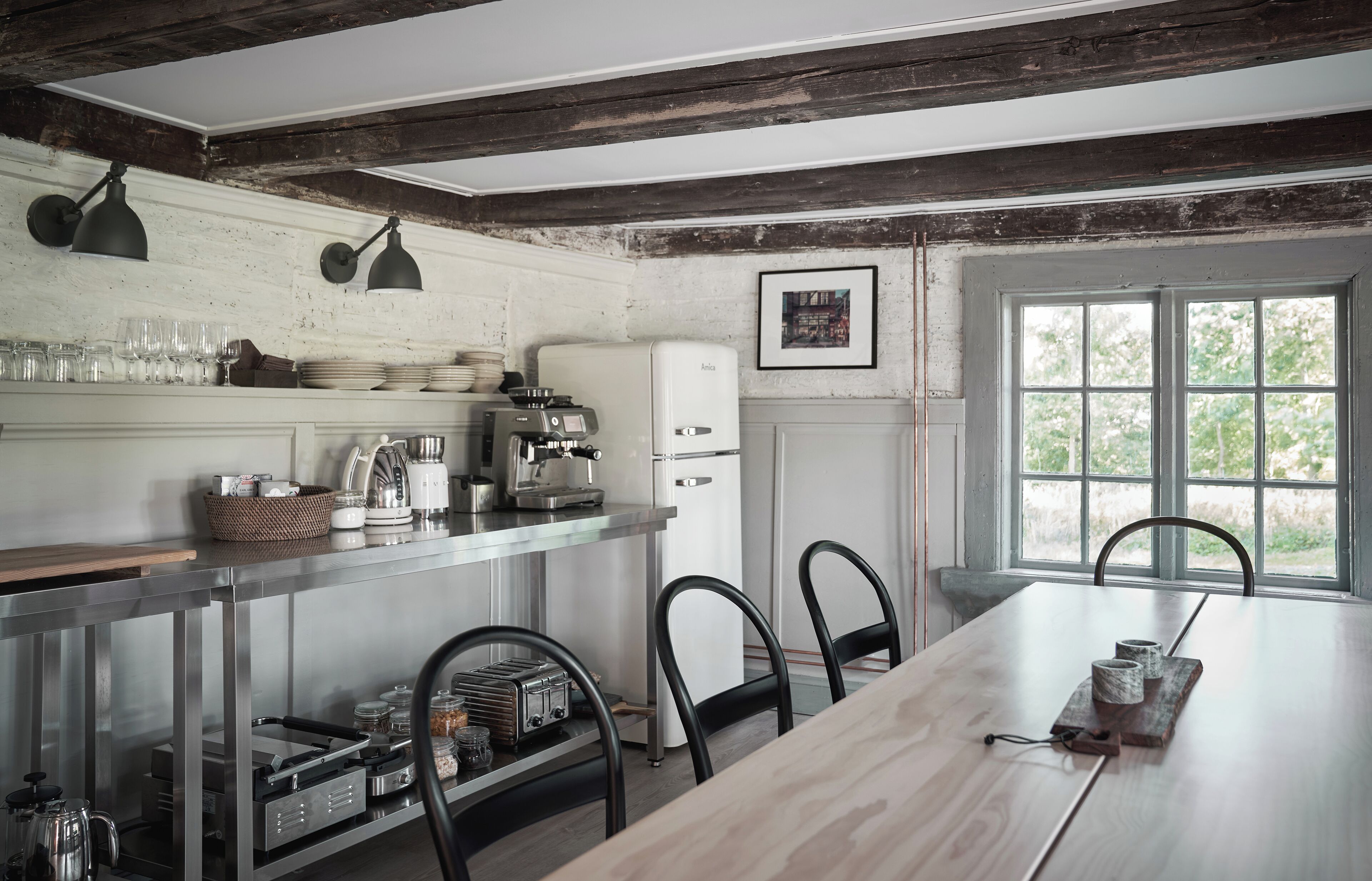 A rustic kitchen with a wooden table, chairs, and a coffee machine.