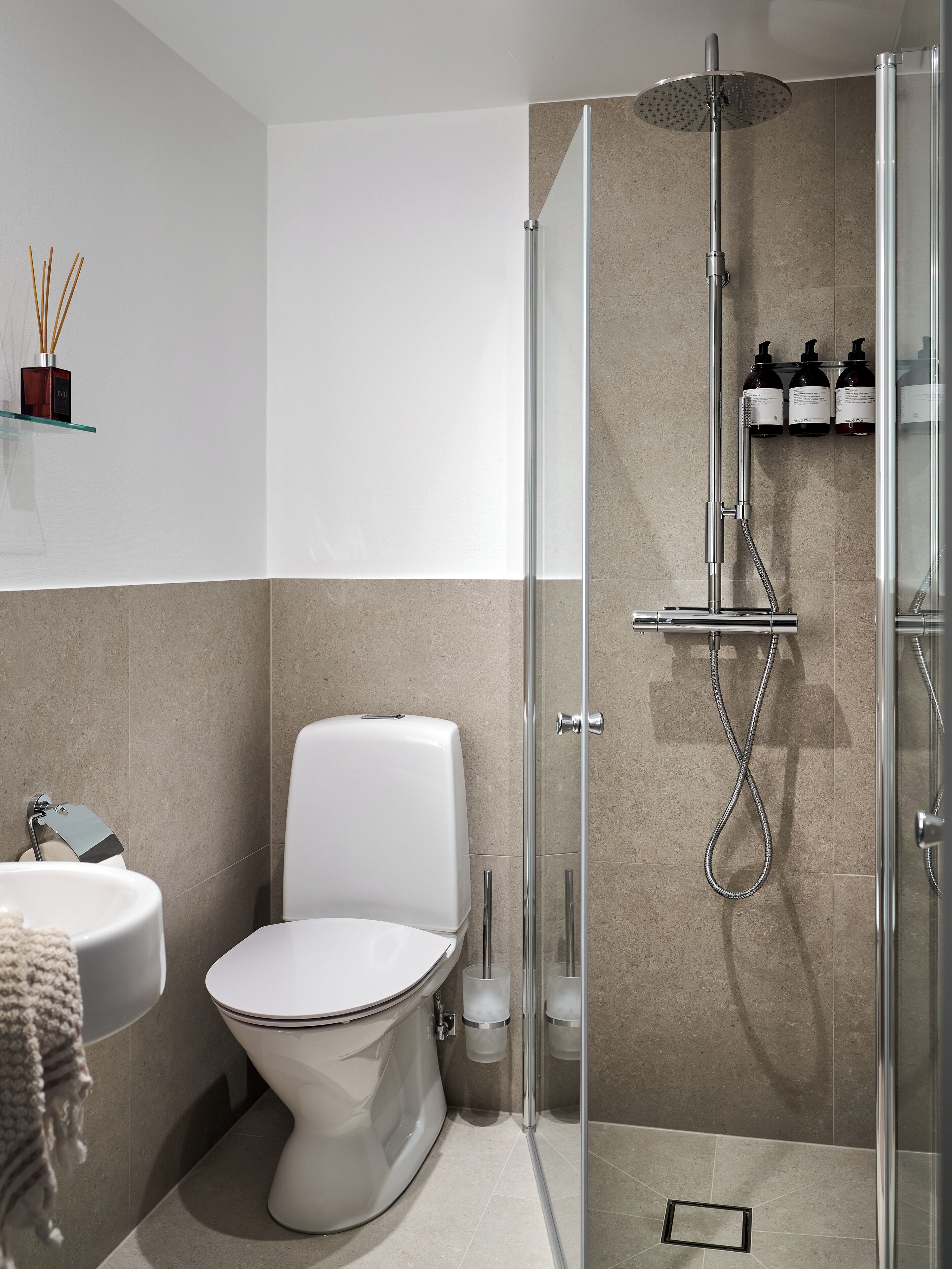 Un baño moderno con inodoro, lavamanos y ducha con mampara de vidrio.