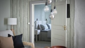 Quarto com parede de madeira, cama com almofadas, mesa de cabeceira e abajur.