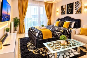 A modern hotel room with a large bed, a sofa, a glass coffee table, and a TV on the wall. - Studio confortable avec espace de travail, télévision, Wi-Fi, balcon et café (Bobigny)