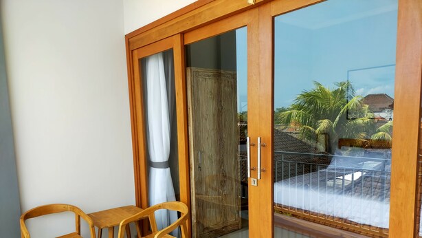 Ein Balkon mit einer Schiebetür, einem Holzstuhl und einem kleinen Tisch.