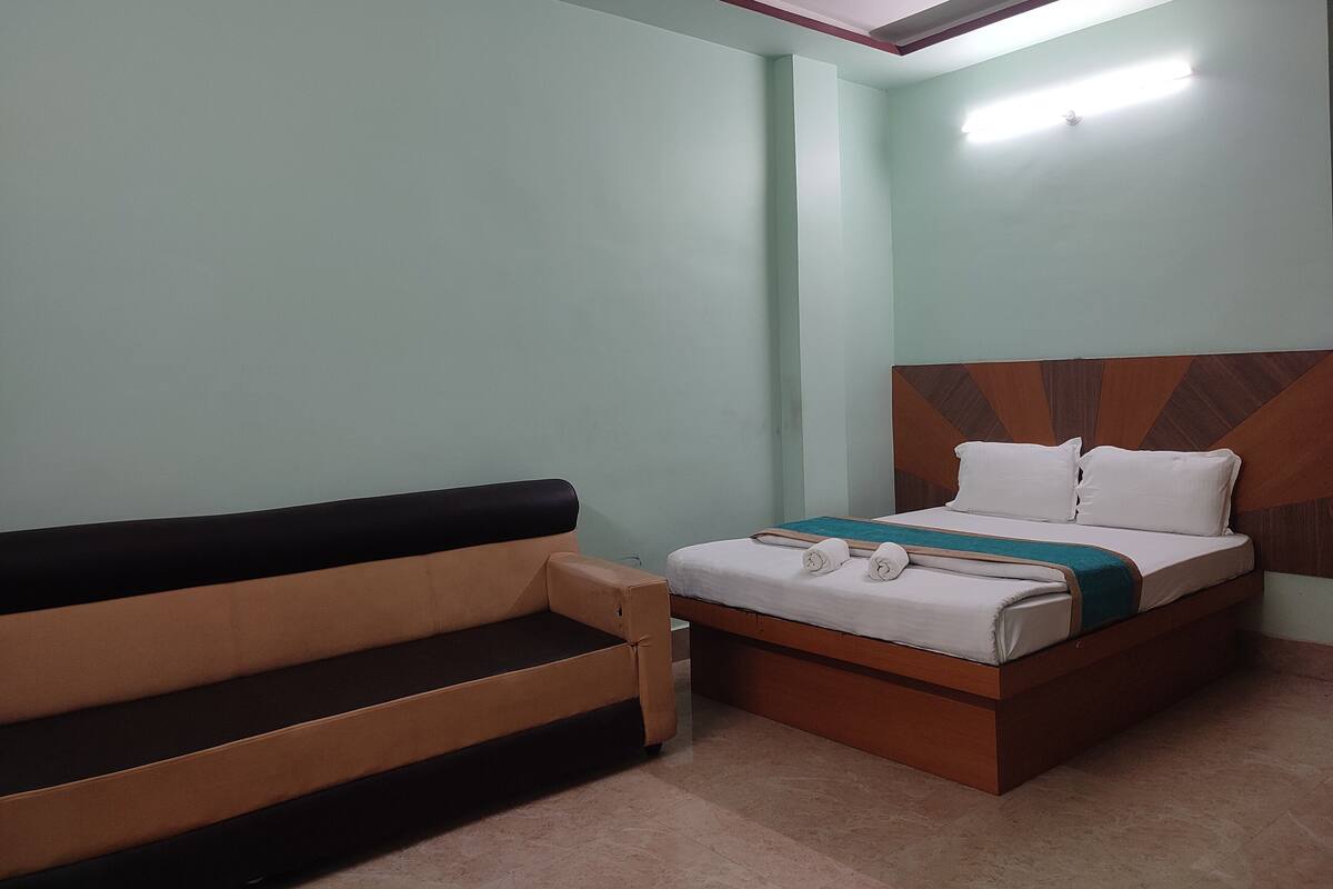 A room with a bed, a sofa, and a tiled floor.
