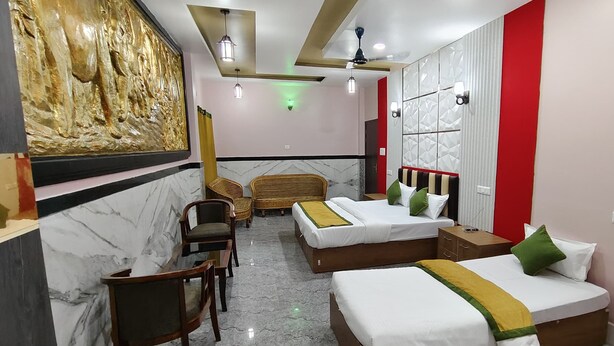 Habitación de hotel con dos camas, un escritorio, sillas y un ventilador de techo.