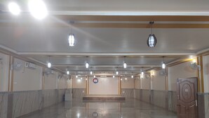 Un vestíbulo amplio con piso pulido, varios ventiladores de techo y una recepción central.