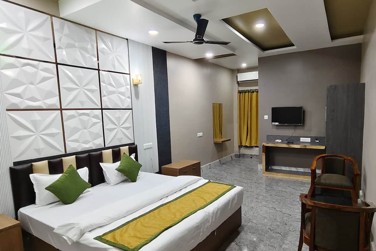 A hotel room with a bed, bedside tables, a desk, a chair, a TV, and a ceiling fan.