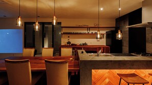 A modern kitchen with a central island, wooden chairs, pendant lighting, and a herringbone-patterned floor. - Innosense Resort -In Chiba Resol- (Sanmu)
